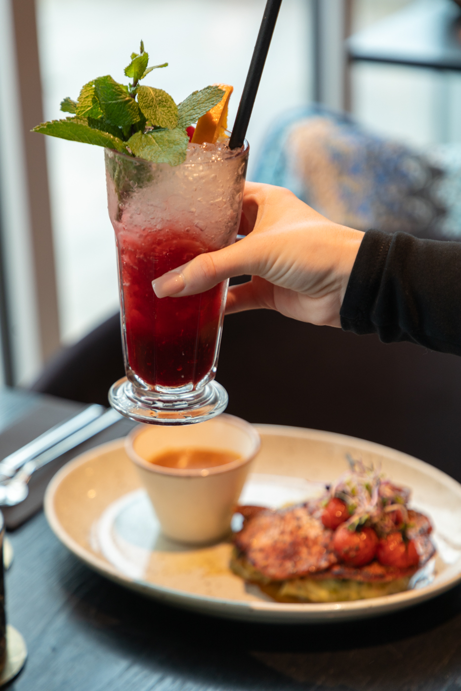 Hand of a girl holding a cocktail on a table in a restaurant.